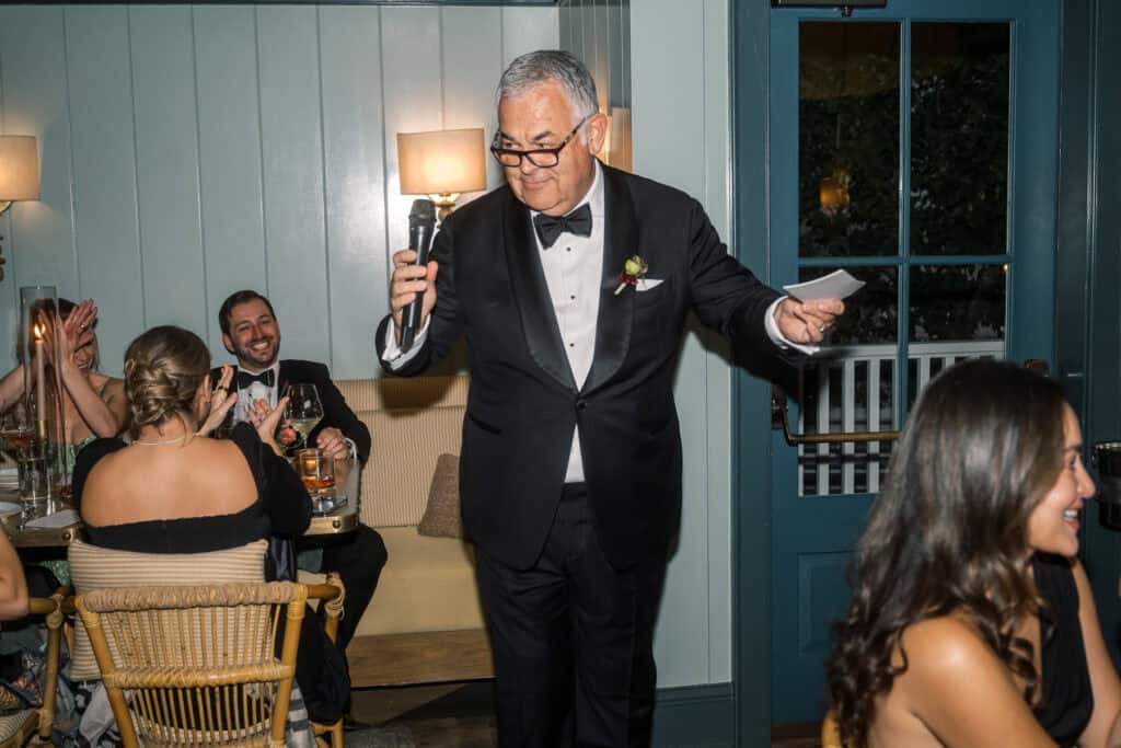 The father of the bride in a tuxedo holding a microphone, captured by Nantucket wedding photographer Kaity Farrell.