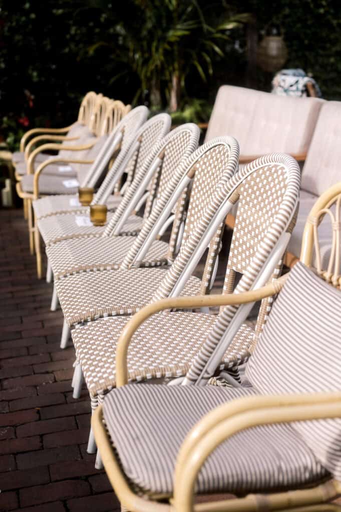 A row of wicker chairs with patterned cushions is lined up on a brick patio, with a sofa and plants in the background—captured beautifully by Nantucket Wedding Photographer Kaity Farrell.